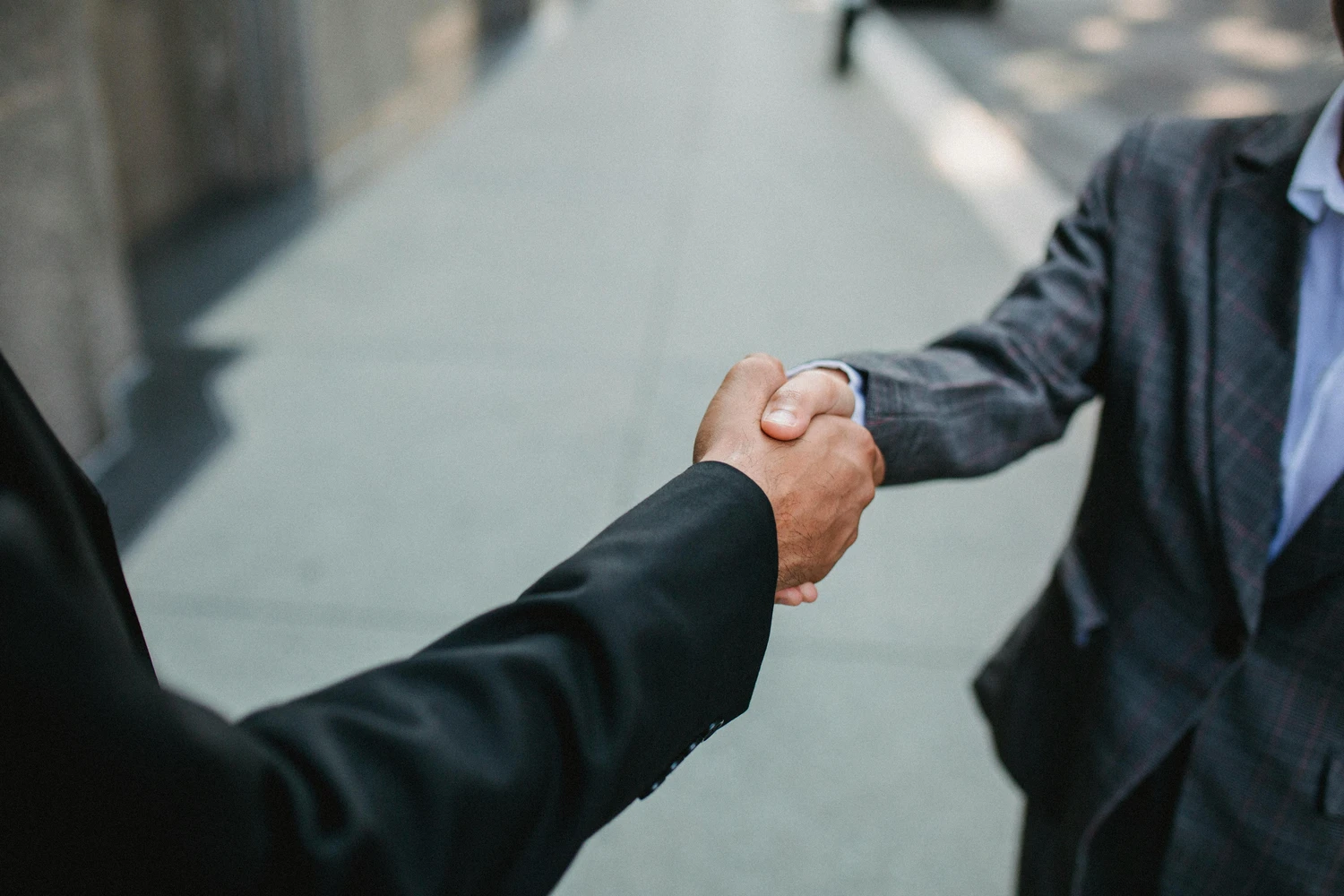 Omega Consulting Group GmbH – Zwei Geschäftsleute geben sich die Hand